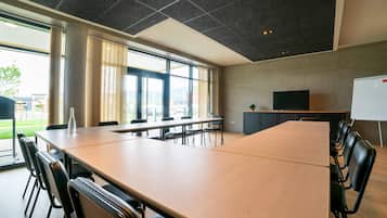 A conference room with a large table, chairs, a whiteboard, and a TV.