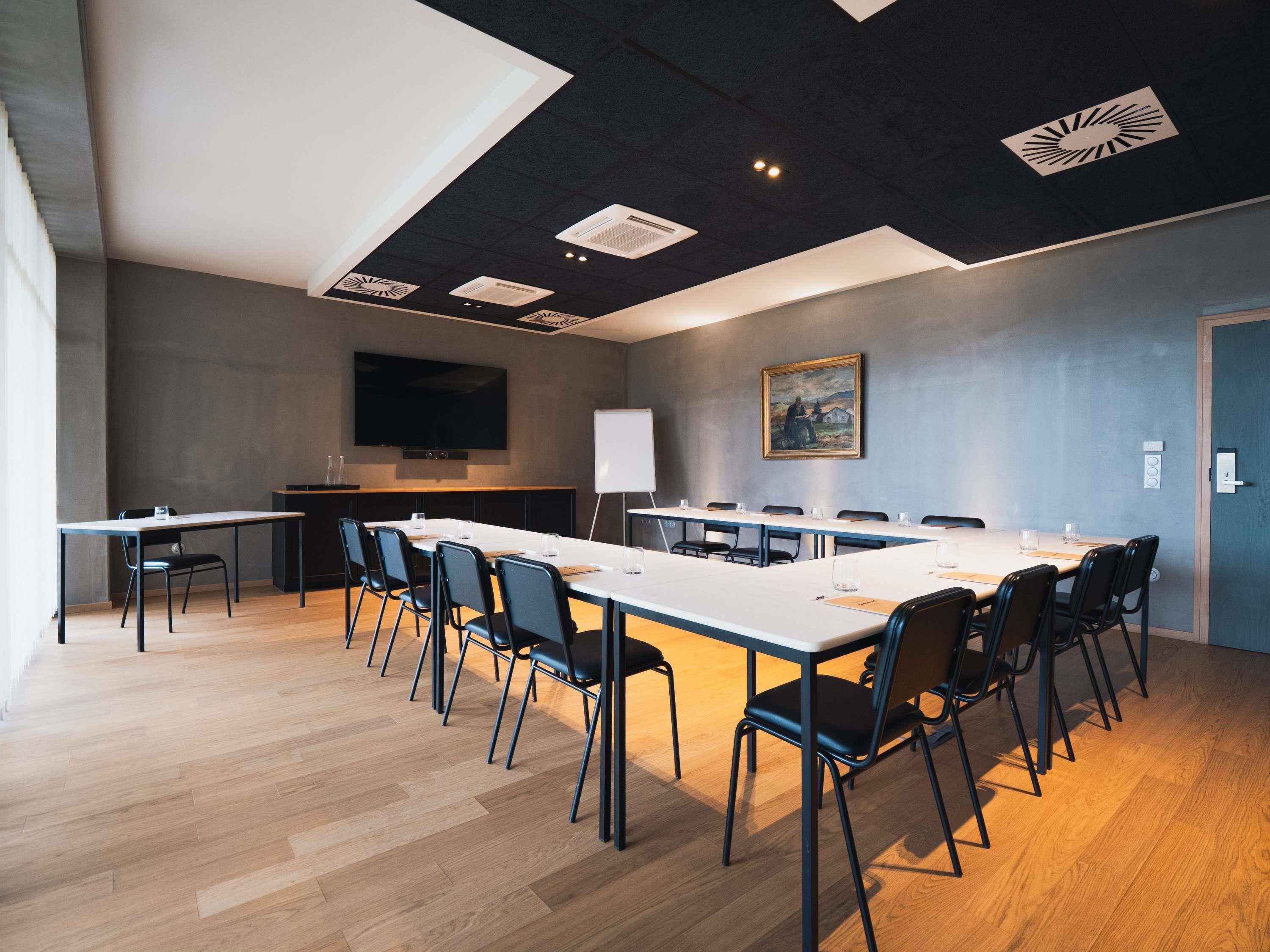 Ein Konferenzraum mit einem langen Tisch, Stühlen, einer Wandtafel und einem Bild an der Wand.