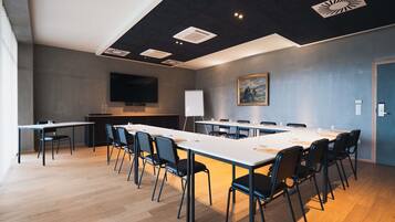 Ein Konferenzraum mit einem langen Tisch, Stühlen, einer Wandtafel und einem Bild an der Wand.