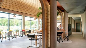 A spacious indoor area with wooden paneling, large windows, and a modern design. - Greet Hotel Cernay Mulhouse (Cernay)