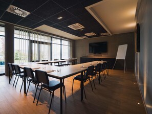 A conference room with a long table, chairs, a whiteboard, and a TV on the wall. - Greet Hotel Cernay Mulhouse (Cernay)
