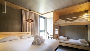 Une chambre avec un lit superposé, un lit simple et un bureau.