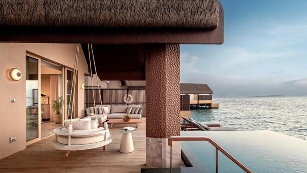 Un área de lounge exterior lujosa con piscina, asientos y vistas al mar.