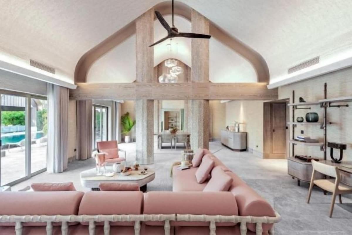 A spacious living area with a high ceiling, a central seating area, and a view of the outdoors.