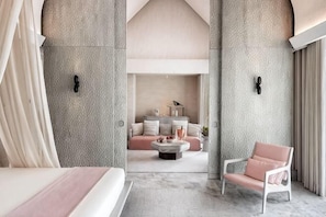 A modern hotel room with a large bed, a sitting area with a sofa and coffee table, and a view into a living area with a fireplace. - JOALI BEING (Bodufushi)