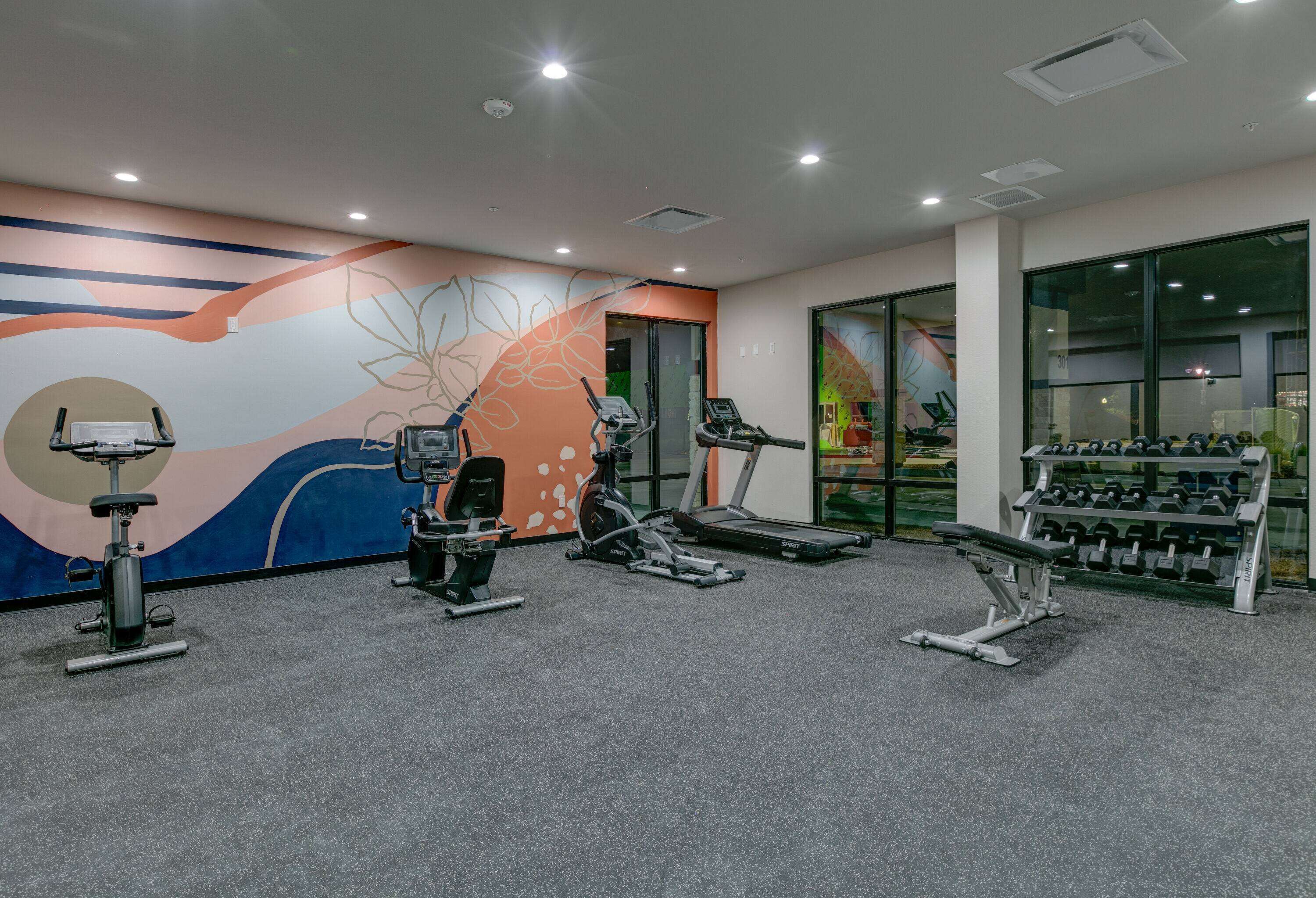 A gym with cardio equipment, weight machines, and dumbbells.