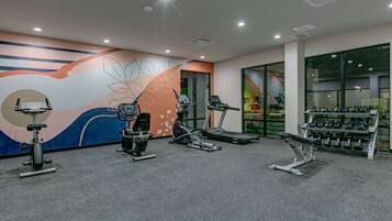 A gym with cardio equipment, weight machines, and dumbbells.