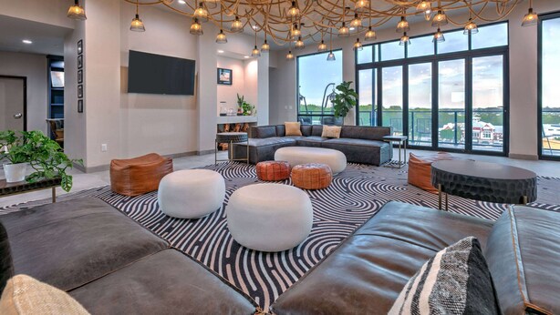 Ein modernes Wohnzimmer mit einem Ecksofa, Poufs und einem gemusterten Teppich.