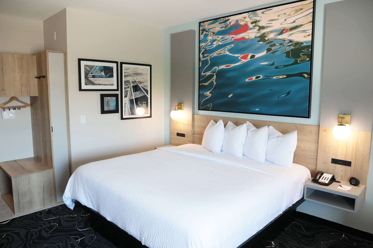 A hotel room with a large bed, a wooden headboard, a wall-mounted telephone, and framed pictures.