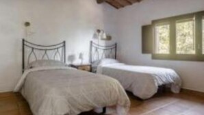 Une chambre avec deux lits simples, une fenêtre donnant sur la forêt et un plafond en bois.