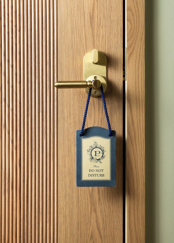 A door with a brass lock and a 'DO NOT DISTURB' sign hanging on a blue rope.