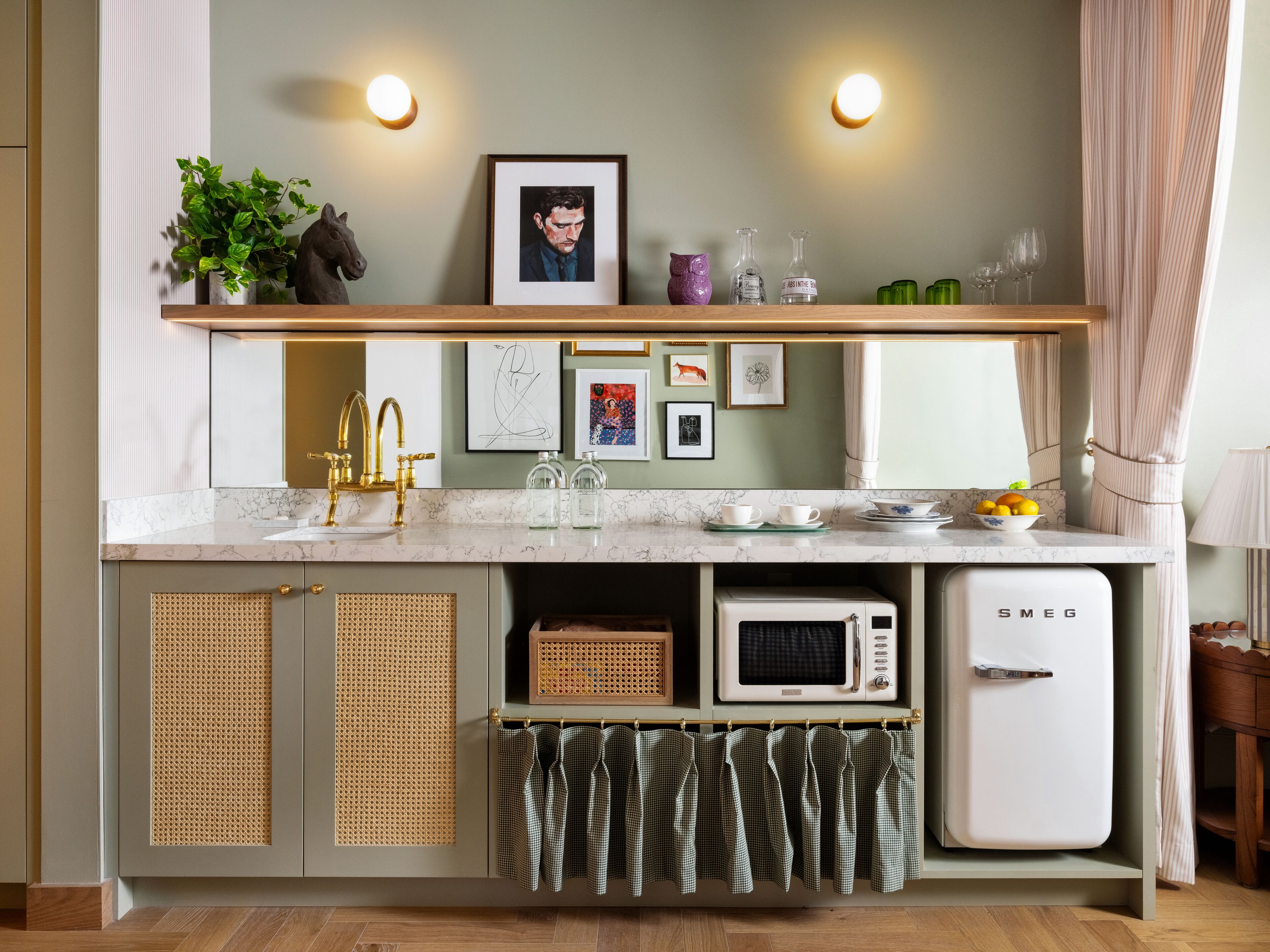 A compact kitchen with a marble countertop, a white refrigerator, a microwave, and a sink with gold faucets.
