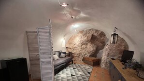 Ein gemütliches Zimmer mit einem Bett, einem Schreibtisch, einem Stuhl und einer großen Felsformation.