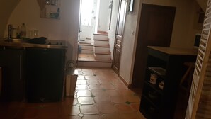 Eine schmale Küche mit Fliesenboden, Spüle und Kühlschrank.