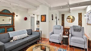 Una sala de estar con un sofá gris, dos sillones, una mesa de centro y una mesa de comedor.