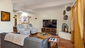 Una sala de estar con sofá, sillones, una mesita de centro, chimenea y televisor.