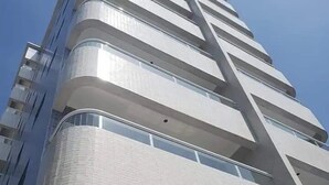 A high-rise building with multiple balconies and a modern architectural design. - Apto com vista pro Mar sacada gourmet (Praia Grande)