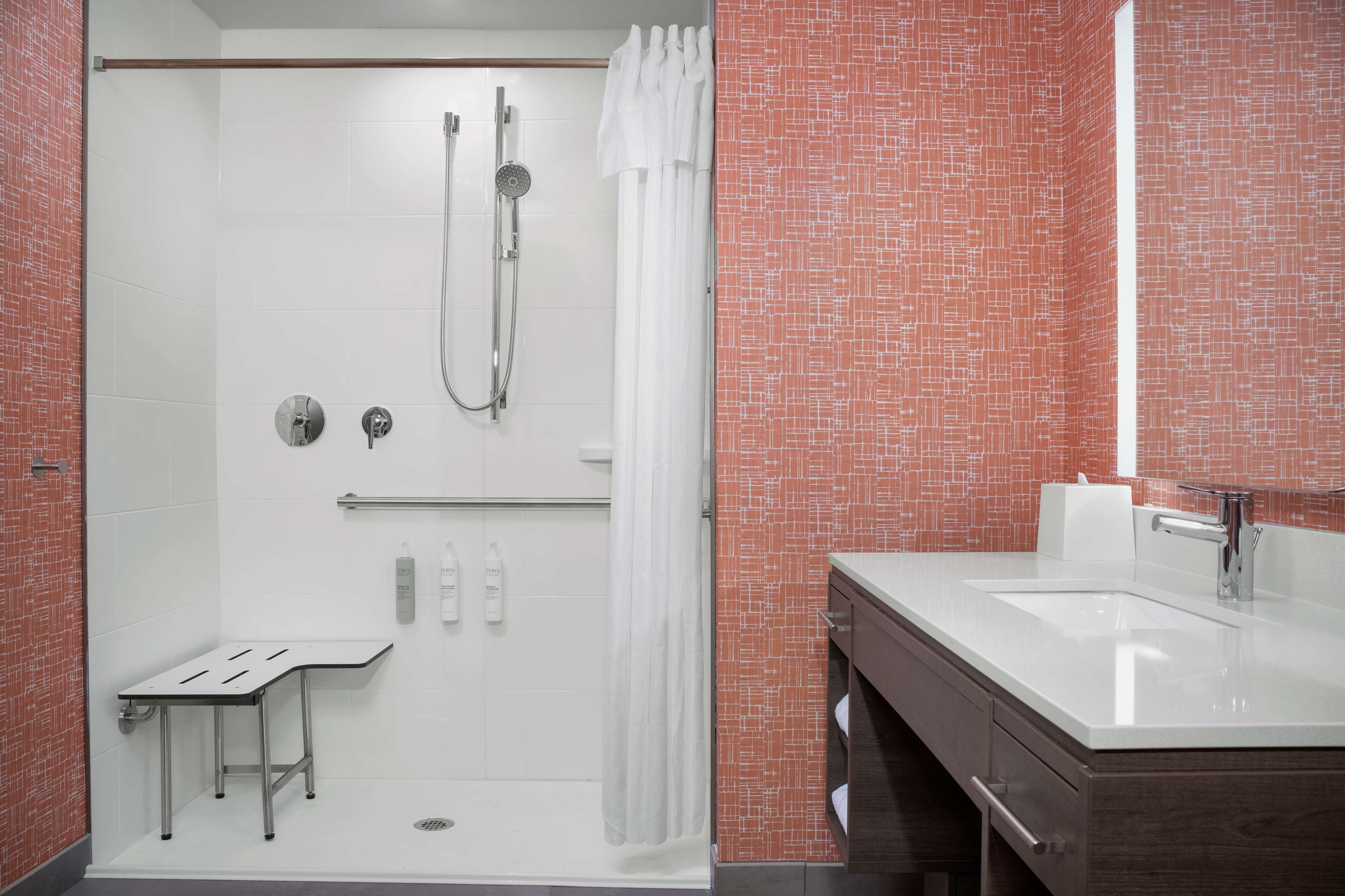 Une salle de bain moderne équipée d’une douche, d’un meuble-lavabo et d’une petite table.