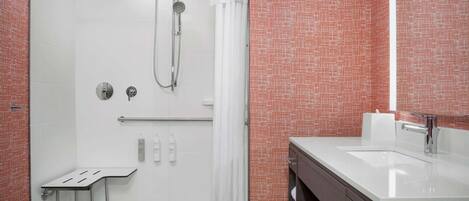Une salle de bain moderne équipée d’une douche, d’un meuble-lavabo et d’une petite table.