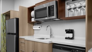 A modern kitchen with a stainless steel refrigerator, a microwave, a coffee maker, and a dishwasher. - Home2 Suites By Hilton Cullman (Cullman)