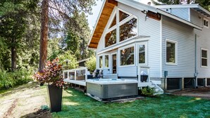 Ein zweistöckiges Haus mit Terrasse, großen Fenstern und einem Whirlpool im Garten.