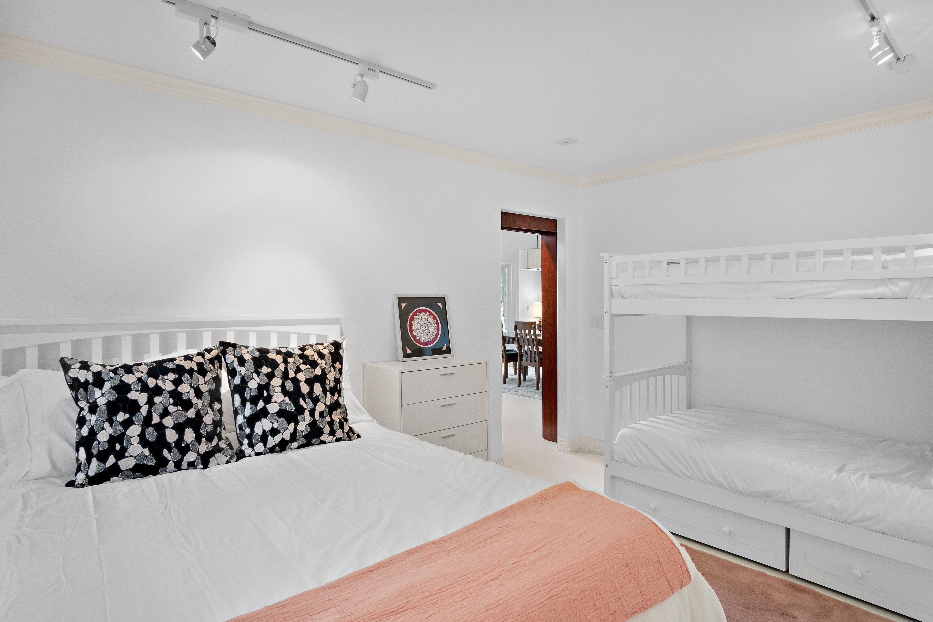 Une chambre avec un lit simple, un lit superposé, une commode et un miroir.
