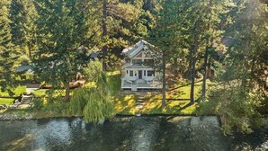 Ein zweistöckiges Haus mit Balkon, umgeben von Bäumen und einem kleinen Teich.