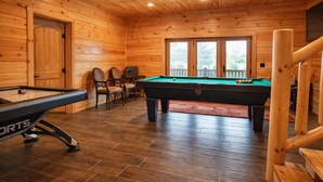 Une table de billard dans un chalet en bois, avec une porte et des fenêtres.
