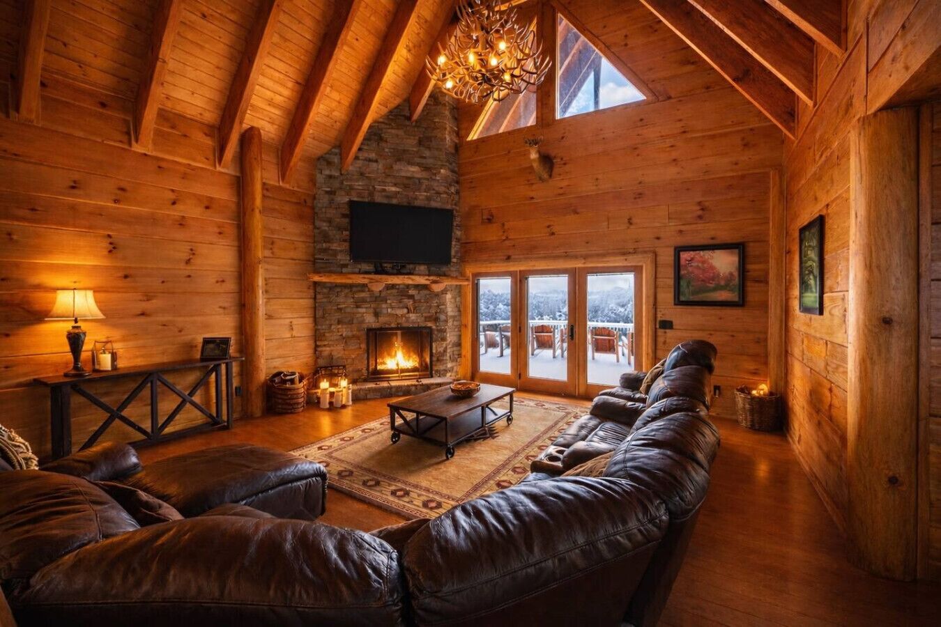 A log cabin interior with a fireplace, leather sofa, and a television mounted on the wall.