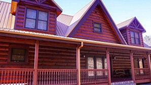 Une cabane en rondins avec une véranda et de nombreuses fenêtres.