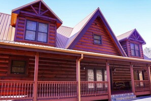 A log cabin with a porch and multiple windows.