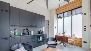 Una cocina moderna con armarios oscuros, un comedor con mesa de madera redonda y un amplio ventanal que proporciona luz natural.