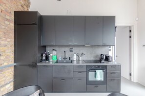 Eine moderne Küche mit grauen Schränken, einer Edelstahl-Spüle und einem eingebauten Ofen.