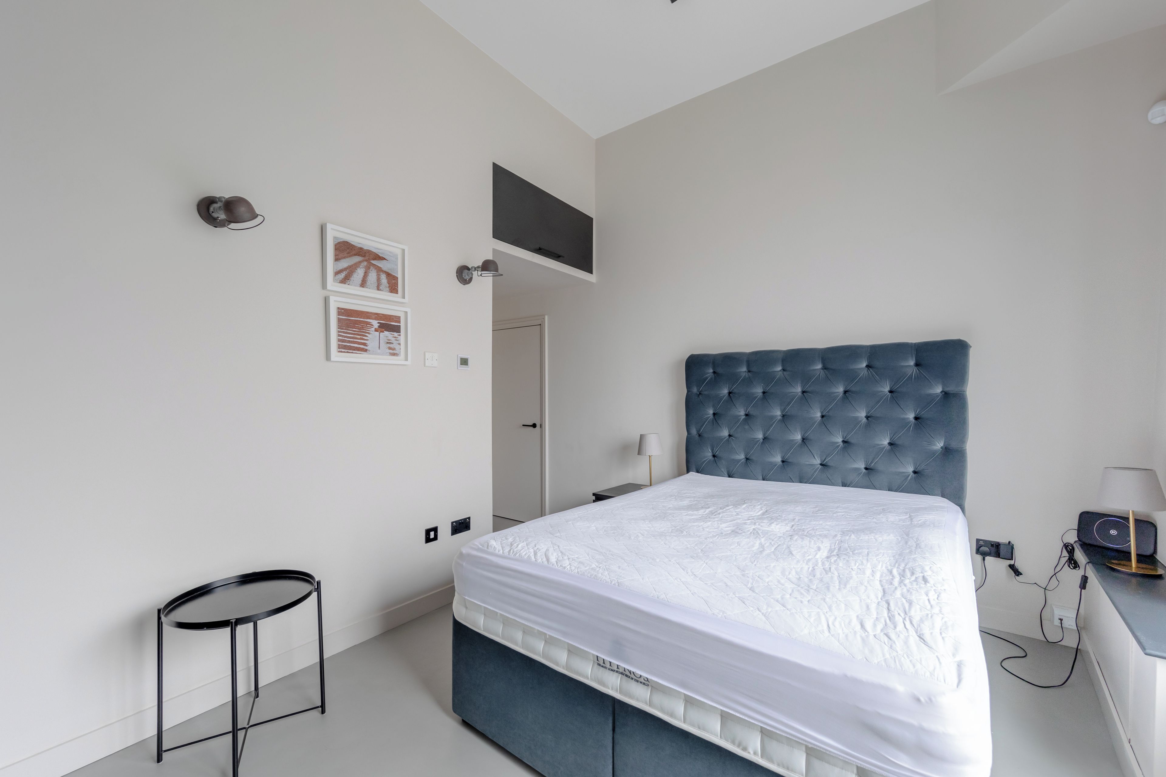 A bedroom with a bed, a desk, a chair, and a television mounted on the wall.