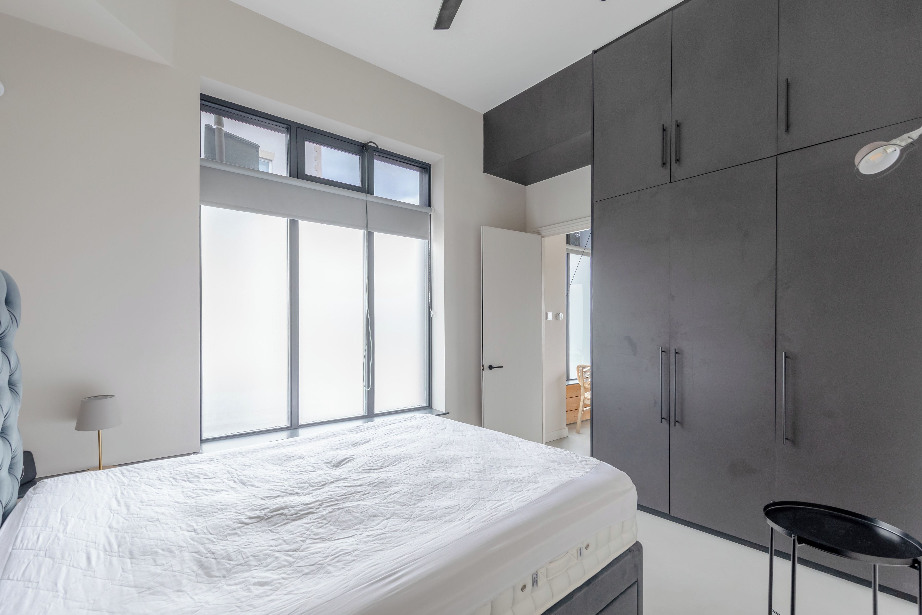 A bedroom with a large bed, a wardrobe, and a window.