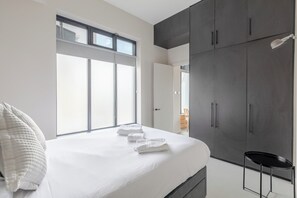 A bedroom with a bed, a wardrobe, and a window. - Stylishly Designed 1BDR Flat by Battersea Park (London)