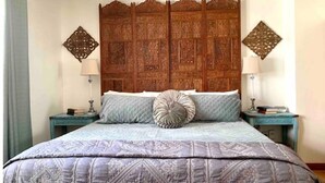 Une chambre à coucher avec un grand lit, deux tables de chevet et une tête de lit en bois.