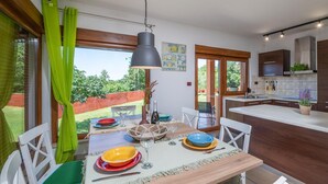 Eine moderne Küche mit Holzausstattung, einer großen Kochinsel und einem Essbereich mit Tisch für vier Personen.