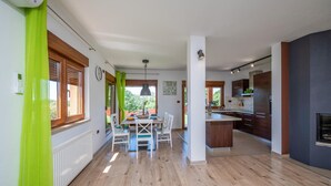 Eine moderne Küche mit Holzausstattung, einem Essbereich mit Tisch und Stühlen sowie Blick ins Freie.