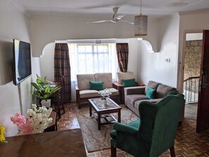 A living room with a sofa, armchairs, a coffee table, and a TV. - Bliss haven apartments  (Nairobi)