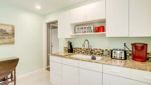 A kitchen with white cabinets, a sink, a toaster, and a coffee maker.