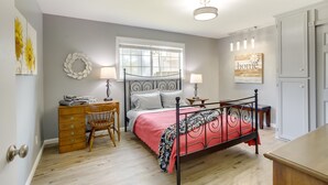 A bedroom with a bed, dresser, chair, and a window with blinds.