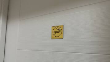 A no-smoking sign on a white textured wall.