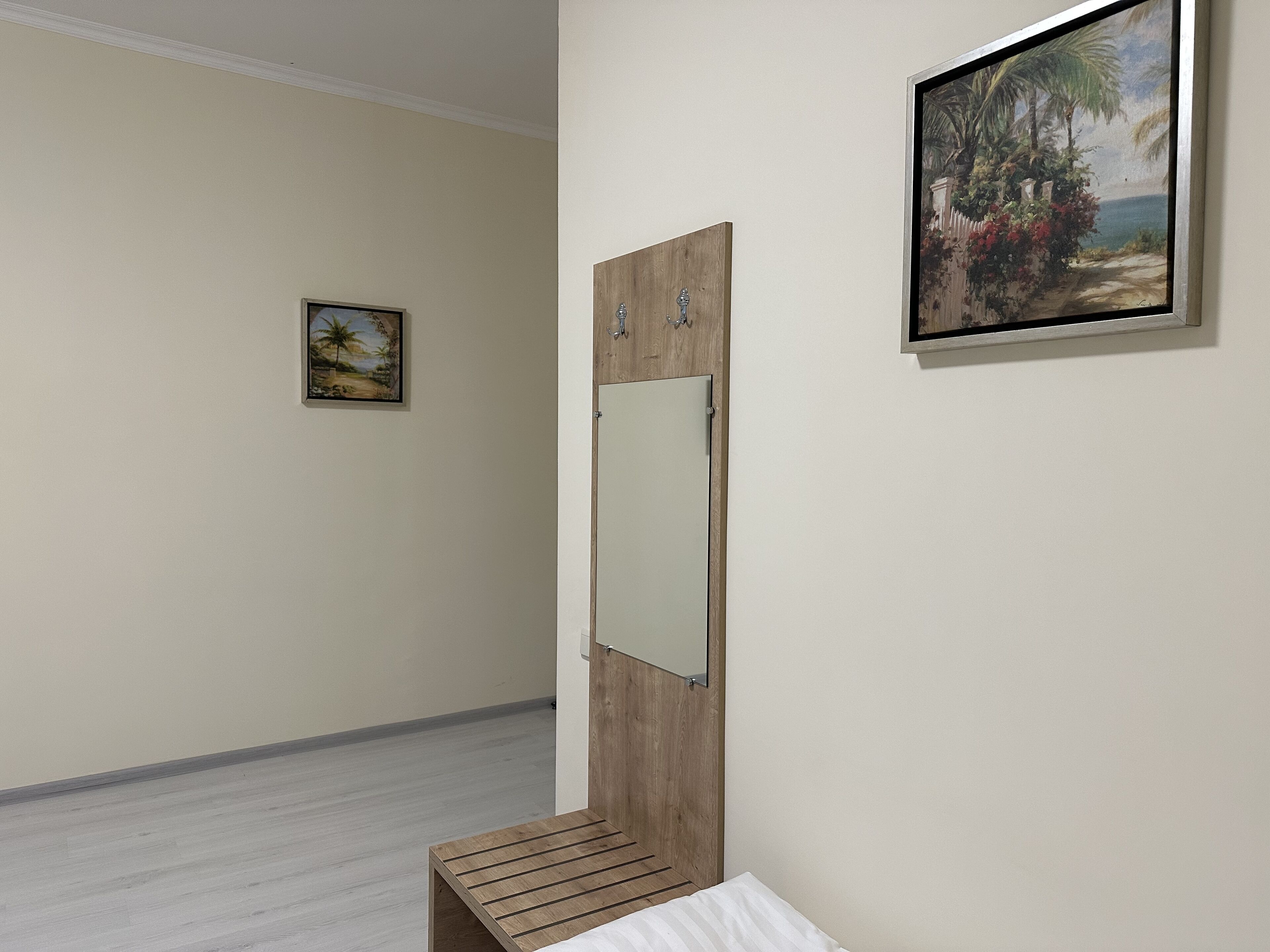 A room with a wooden bench, a small table, and two framed paintings on the wall.