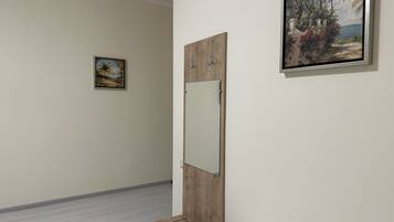A room with a wooden bench, a small table, and two framed paintings on the wall.
