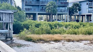A beachfront property with multiple-story buildings, a covered walkway, and a sandy beach area. - Fenimore Mill 10E - Pool, Hot Tub, Boat Parking! (Cedar Key)