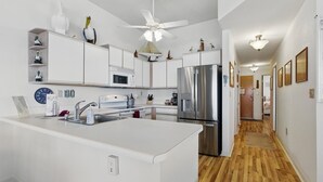 Eine moderne Küche mit weißen Schränken, einem Edelstahl-Kühlschrank und einer zentralen Kochinsel mit Spüle.