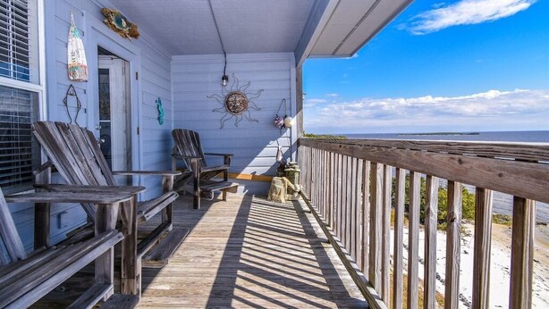 A wooden deck with benches, a ceiling fan, and a decorative sun on the wall. - Fenimore Mill 2D - High Tide By the Gulf! (Cedar Key)