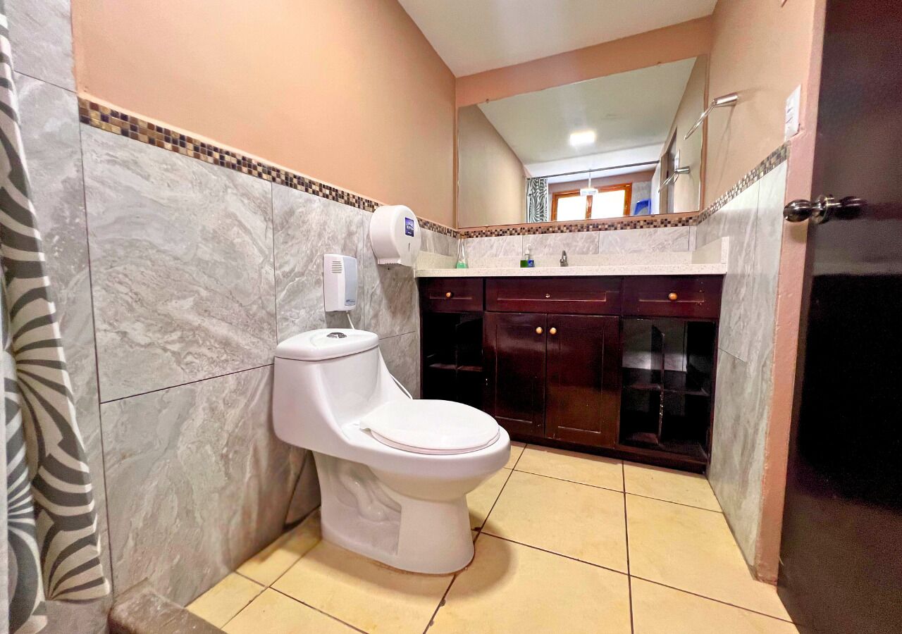 Un baño con inodoro, secamanos y espejo.