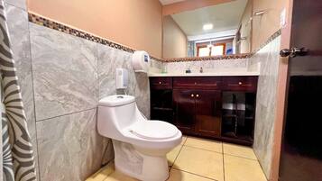 Un baño con inodoro, secamanos y espejo.